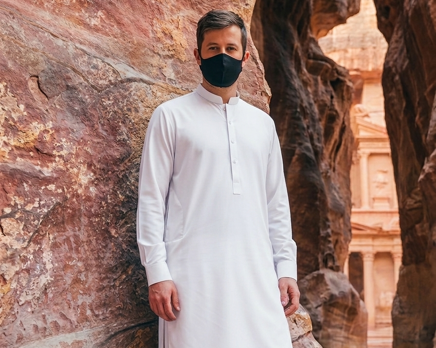 Man in white traditional outfit  standing in a rocky canyon.